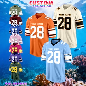 May include: A selection of football jerseys in colours such as orange, cream, and blue. Each jersey displays the number 28 and has space for a team name. The image includes the text "CUSTOM ADD DESIGN" and "48 colours".