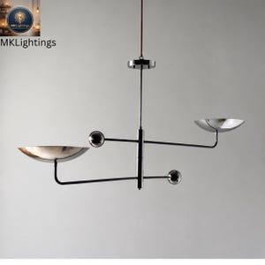 Op de afbeelding: Moderne kroonluchter met een zwarte en chromen afwerking. De armatuur heeft twee komvormige kappen en twee bolvormige accenten. De tekst "MKLightings" is zichtbaar linksboven.