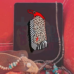 Könnte beinhalten: Grafische Darstellung einer roten und schwarzen Cowboy-Weste mit Leoparden-, Schach- und Zebramuster. Ein roter Blitz befindet sich auf der Weste. Das Bild befindet sich auf einem dunklen Hintergrund mit rotem Rand und einer Halskette.
