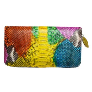 Peut inclure: Un portefeuille rectangulaire avec un motif de peau de serpent multicolore vibrant. Les couleurs comprennent le rouge, l'orange, le jaune, le vert, le bleu et le violet. Le portefeuille a une fermeture éclair avec une petite tirette vert olive.