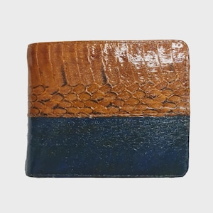 May include: A bi-fold wallet with a two-tone design. The top section is brown with a textured, snake-like pattern, while the bottom is a solid navy blue. The wallet is rectangular and appears to be made of leather.