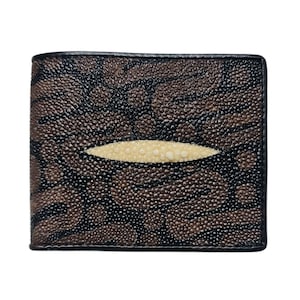 May include: A bi-fold wallet with a distinctive textured pattern. The wallet has a brown and black design with a central cream-coloured oval. The edges are trimmed with black. This wallet is a stylish accessory.