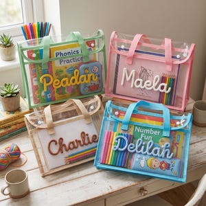 May include: Four clear tote bags with coloured handles and personalised names. Each bag contains books, pencils, and markers. The bags are in green, pink, beige, and blue, and are on a wooden table.