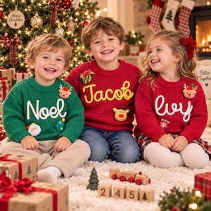 May include: Three children wearing personalized knit sweaters. The left child wears a green sweater with the name Noel, the center child wears a red sweater with the name Jacob, and the right child wears a red sweater with the name Ivy.