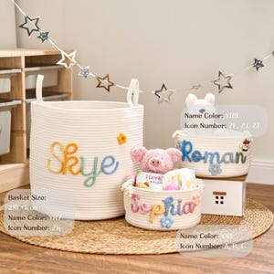 May include: Three cream-coloured rope baskets of different sizes, each with a name embroidered in colourful thread. The largest basket says "Skye", the medium one says "Roman", and the smallest says "Sophia". A pink pig and other items are inside the baskets.