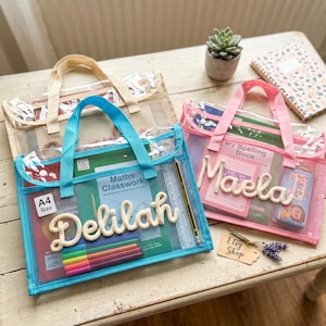 May include: Three rectangular A4 size mesh zipper pouches with handles in blue, pink, and beige. The blue pouch features the name Delilah in white rope lettering, while the pink pouch features the name Maela in white rope lettering.