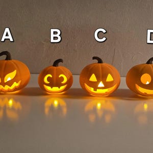 May include: Four orange pumpkin-shaped lanterns labeled A, B, C, and D, each featuring a unique carved face illuminated from within by a warm yellow light. The pumpkins have brown stems and distinct facial expressions.