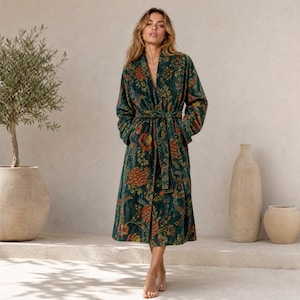 Puede incluir: Una bata de manga larga en un tono verde bosque profundo, con un vibrante estampado floral con motivos botánicos en naranja, amarillo y verde. La prenda incluye un cinturón de tela a juego en la cintura y cuello esmoquin, llegando a media pantorrilla.