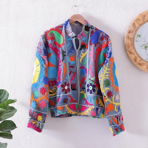 Peut inclure: Veste de bombardier grise avec broderies colorées. La veste est dotée d'une fermeture éclair et ornée de motifs floraux et cachemire aux tons de rouge, bleu, vert, jaune et rose. Les poignets et l'ourlet sont bordés d'un tissu rose contrastant.