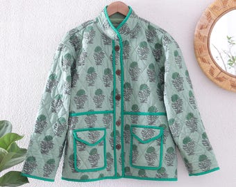 May include: A light green quilted jacket with a floral pattern in shades of green and gray. The jacket has a stand-up collar, four brown buttons, and two front pockets. The edges are trimmed with a bright green piping.