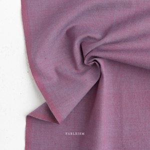 May include: A piece of solid mauve-colored fabric with a visible woven texture. The fabric is draped to show folds and depth. The word FABLEISM is printed in small white capital letters near the bottom center of the fabric surface.