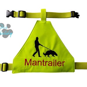 Könnte beinhalten: Ein neongrünes Hundegeschirr mit schwarzen Schnallen und Riemen. Das Geschirr zeigt eine schwarze Silhouette einer Person, die einen Hund führt, mit dem Wort "Mantraller" in Rot.