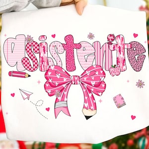 Puede incluir: Sudadera blanca con la palabra "Assistant" en rosa, adornada con un gran lazo rosa, un lápiz, una manzana e ilustraciones escolares. El diseño presenta varios patrones rosas y una fuente juguetona.