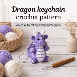 May include: A purple and white crocheted dragon keychain with small horns and wings, accompanied by a wooden crochet hook and balls of yarn. The text reads: Dragon keychain crochet pattern. An easy-to-follow amigurumi guide.