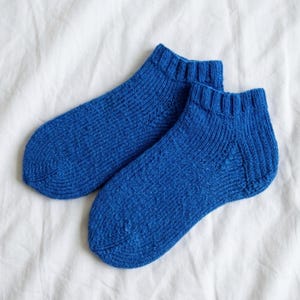 May include: A pair of ankle-length socks in a vibrant royal blue color. These socks feature a knitted texture with a ribbed cuff at the top and a reinforced heel and toe section, showcasing a consistent stitch pattern throughout the fabric.