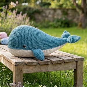 Peut inclure: Une peluche baleine crochetée bleu sarcelle avec un ventre crème et un corps arrondi et lisse. La baleine présente un œil unique sombre et brillant sur le côté, une petite nageoire latérale et une nageoire caudale bifide, le tout en laine.