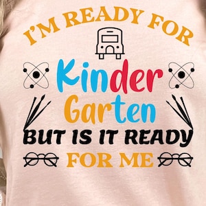 Peut inclure: T-shirt pêche avec l'inscription "I'M READY FOR Kindergarten BUT IS IT READY FOR ME" en jaune, bleu, rouge et noir. Le t-shirt présente un dessin de bus scolaire, des symboles d'atomes et des lunettes.