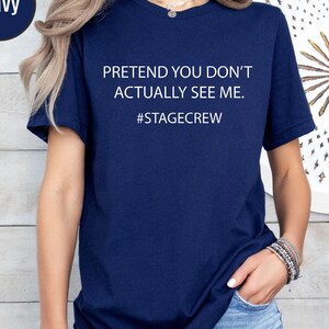 Può includere: Una t-shirt a maniche corte blu navy con il testo bianco "PRETEND YOU DON'T ACTUALLY SEE ME." seguito dall'hashtag "#STAGECREW" centrato sul petto. Il capo presenta un classico girocollo e una vestibilità standard.