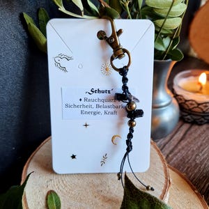 Könnte beinhalten: Ein Set aus drei Keramikbechern mit gesprenkelter, matter Oberfläche. Die Becher sind in Creme-, Hellgrau- und Dunkelgrautönen gehalten. Jeder Becher hat ein schlichtes, minimalistisches Design.