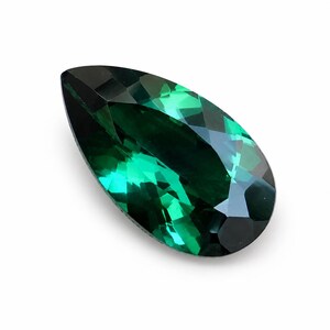 May include: A pear-shaped gemstone with a deep forest green color and a faceted surface. The stone features a pointed top and a rounded base, with multiple triangular and trapezoidal facets that reflect light to create a brilliant, sparkling appearance.