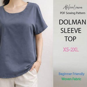 May include: A slate blue dolman sleeve top with a round neckline. The text reads: AtelierLiana, PDF Sewing Pattern, DOLMAN SLEEVE TOP, XS-2XL, Beginner Friendly, Woven Fabric. The top is shown on a person wearing light-colored pants.