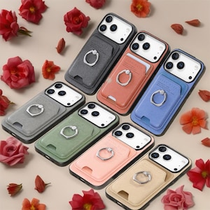 May include: A selection of mobile phone cases in various colours, each with a cardholder and ring holder. The cases are in shades of grey, coral, blue, green, pink, and beige. Each case features a silver ring holder and a card slot.