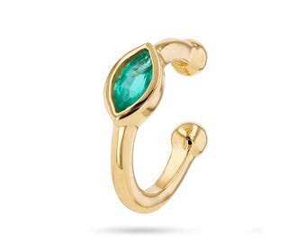 May include: A gold-colored ear cuff featuring a marquise-cut, emerald-green gemstone. The cuff curves around the ear, with a small ball at each end. The gemstone is set in a bezel setting, adding a touch of elegance.