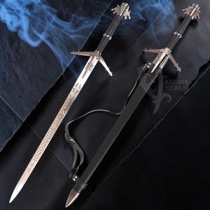 May include: Two silver swords with black handles and crossguards are displayed. One sword is unsheathed, revealing etched details on the blade. The other sword is in a black sheath with a leather strap. The swords have ornate pommels and are set against a dark background.