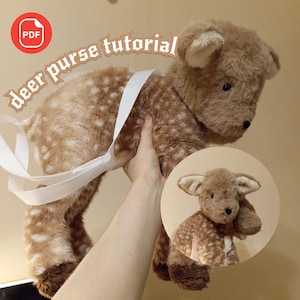 May include: A plush deer purse with a white strap, held up by a hand. The deer is brown with white spots and has a small, round head. The text "deer purse tutorial" is arched above the deer.