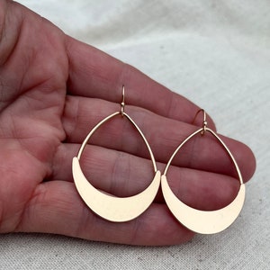 Puede incluir: Un par de pendientes colgantes de color dorado con forma de media luna. Los pendientes est&aacute;n hechos de metal y tienen un dise&ntilde;o simple y moderno.