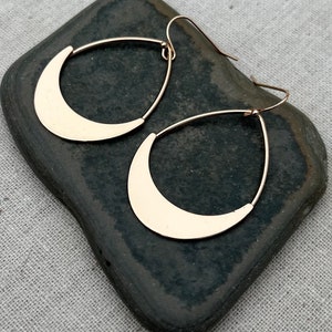 Puede incluir: Un par de pendientes colgantes de media luna de color dorado. Los pendientes est&aacute;n hechos de metal y tienen un dise&ntilde;o simple y moderno.