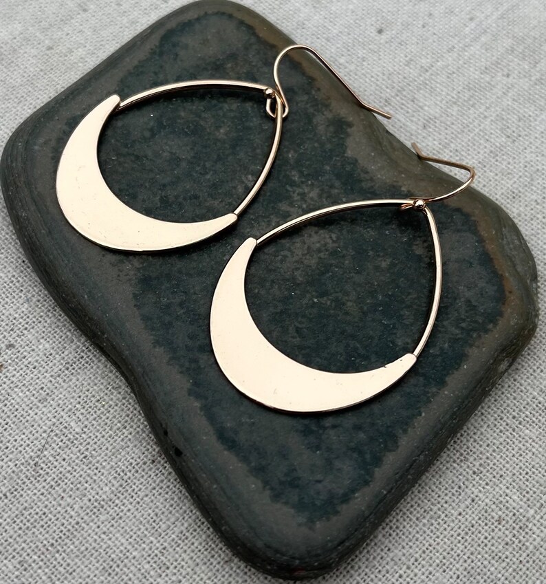 Puede incluir: Un par de pendientes colgantes de media luna de color dorado. Los pendientes est&aacute;n hechos de metal y tienen un dise&ntilde;o simple y moderno.
