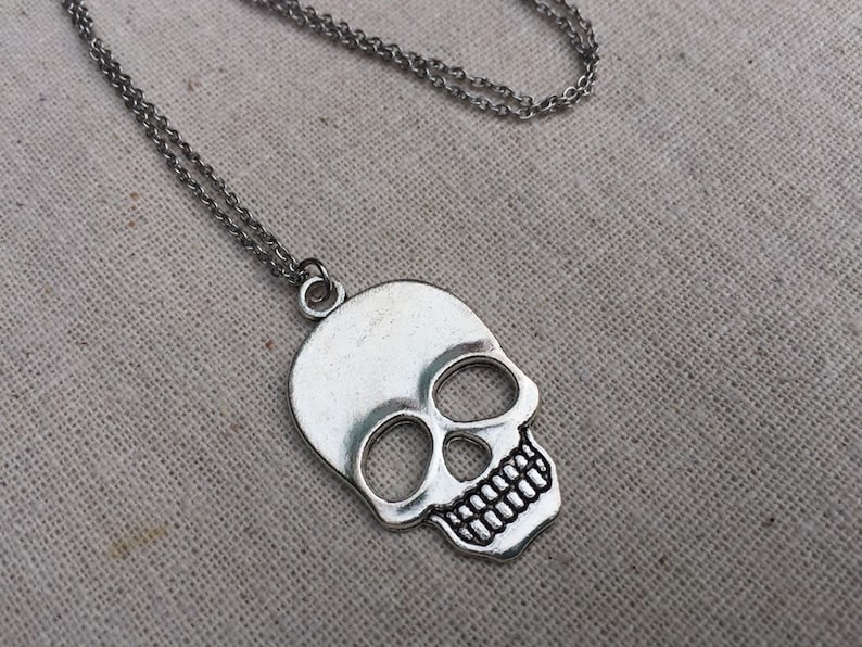 May include: A silver skull pendant necklace with a double chain.
