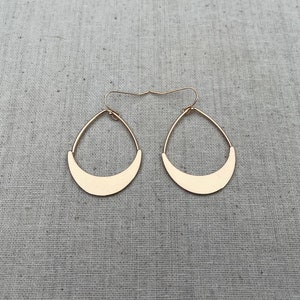 Puede incluir: Un par de pendientes de color dorado con forma de media luna. Los pendientes son simples y elegantes.