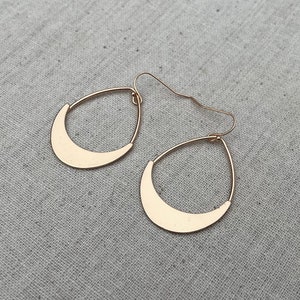 Puede incluir: Un par de pendientes de media luna de oro. Los pendientes son simples y elegantes.