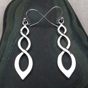 Puede incluir: Pendientes de plata con un diseño retorcido en forma de infinito. Los pendientes miden aproximadamente 5 cm de largo.
