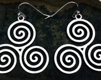 May include: A pair of silver-toned metal earrings featuring a triskelion design composed of three interconnected spirals. Each earring hangs from a simple silver-toned hook wire, showcasing a flat, cut-out pattern with a polished metallic finish.