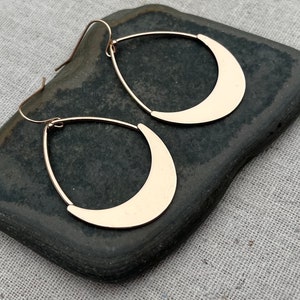 Puede incluir: Un par de pendientes de media luna de color dorado. Los pendientes son colgantes y tienen un dise&ntilde;o simple y moderno.