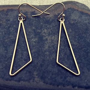 May include: A pair of gold-toned triangle shaped earrings with a simple geometric design.