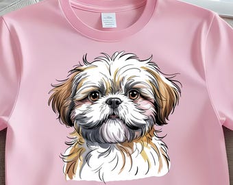 May include: A light pink t-shirt featuring a detailed illustration of a Shih Tzu dog. The dog has brown and white fur, with large brown eyes and a black nose. The shirt has a crew neck and short sleeves.