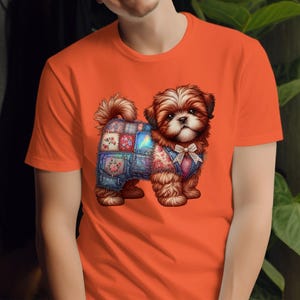 Puede incluir: Camiseta naranja con una ilustración detallada de un cachorro Shih Tzu. El cachorro lleva un chaleco vaquero patchwork y una pajarita. El cachorro tiene pelo marrón y blanco. La camiseta es de color naranja liso.