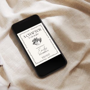 May include: A black smartphone displays a digital invitation with the text "A Chapter to Remember." The invitation features a floral border and the words "Emily's 30th Birthday." The phone rests on a beige fabric surface.