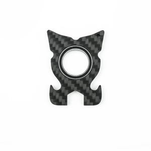 May include: A black and gray carbon fiber multi-tool with a central ring and a textured pattern. The tool has a unique shape with curved edges and a small hole at the top.