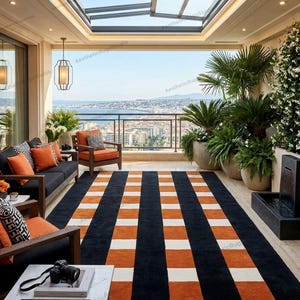 Könnte beinhalten: Ein Balkon mit einem gestreiften Teppich in Schwarz, Orange und Weiß. Der Raum ist mit schwarzen Sofas, Holzstühlen und Topfpflanzen eingerichtet. Der Balkon hat ein Glasdach und bietet einen Blick auf die Stadt. Der Teppich misst ca. 300 cm x 200 cm.