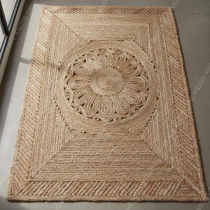 Full angled view custom braided jute area rug with central floral motif on gray floor modern style.