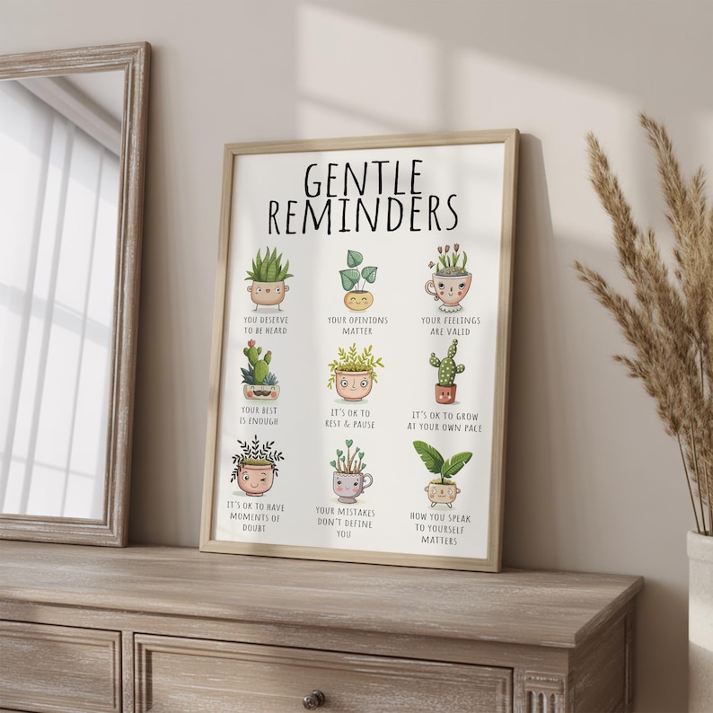 Puede incluir: Un cuadro enmarcado con las palabras "GENTLE REMINDERS" y dibujos de plantas en macetas con afirmaciones positivas. Incluye frases como "Tus sentimientos son v&aacute;lidos" y "Est&aacute; bien descansar". El marco es de color marr&oacute;n claro.