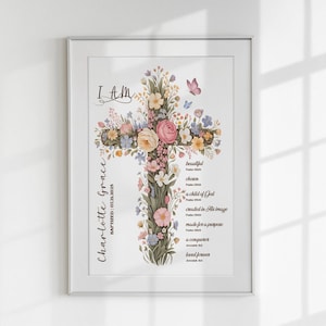 Può includere: Stampa artistica incorniciata con un design a croce floreale. La croce è adornata con fiori rosa, gialli e blu, con una farfalla. Il testo include "I AM", "Charlotte Grace" e frasi ispiratrici.