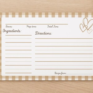 May include: A recipe card with a beige and white gingham border. The card has spaces for ingredients and directions, with the words "Ingredients" and "Directions" printed on it. Two hearts are drawn in the upper right corner. Wheat stalks are in the background.