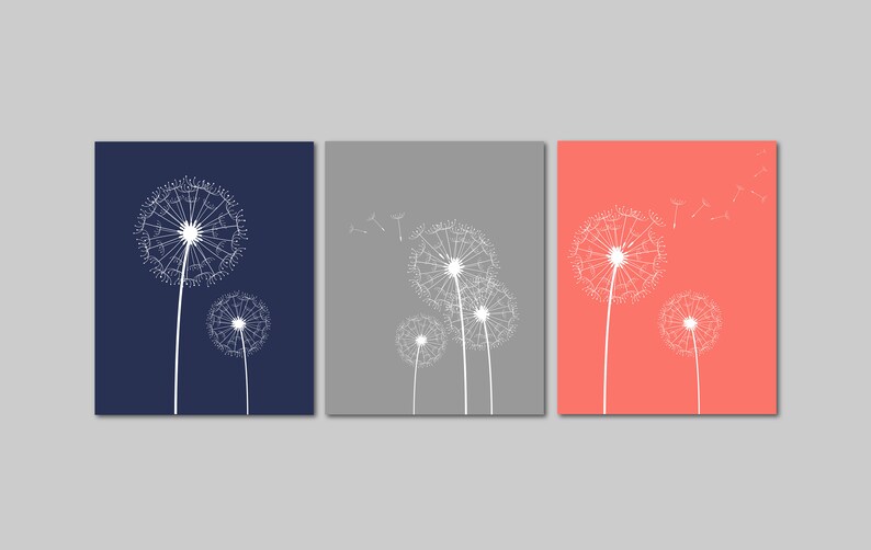 以下が含まれることがあります： 白いタンポポのイラストが描かれた正方形のキャンバスが3枚。キャンバスの色はネイビーブルー、グレー、コーラルです。