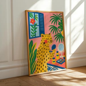 May include: A framed art print depicting a yellow leopard applying makeup. The illustration has a pink backdrop with a window, plants, and a table with makeup items. The leopard has black spots and is holding a brush and a compact mirror.